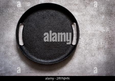 Empty rustic black cast iron plate On a concrete background. Top Stock Photo