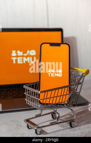 Gdansk, Poland - March 2023 Temu app icon in screen of MacBook Apple computer laptop and mobile Iphone with shopping cart. Temu Stock Photo