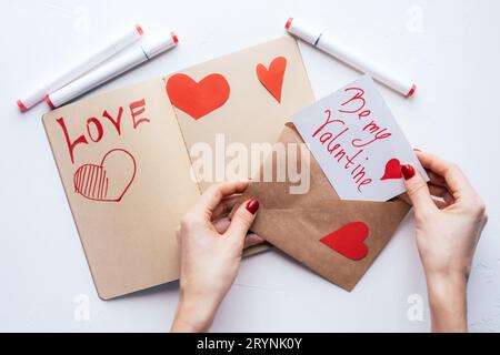 Female hands put a written valentine in an envelope. Declaration of love and a holiday surprise. Stock Photo