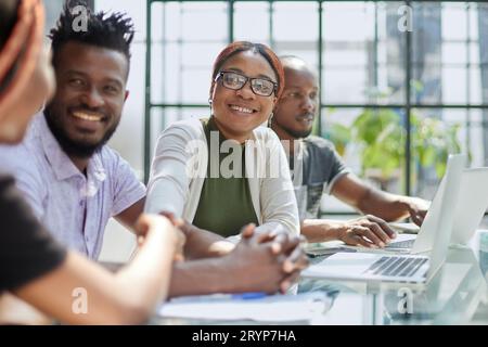 Diverse group of smiling businesspeople talking together around Stock Photo