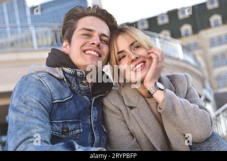 Happy couple or friends hugging and sharing a tablet in the street Stock Photo