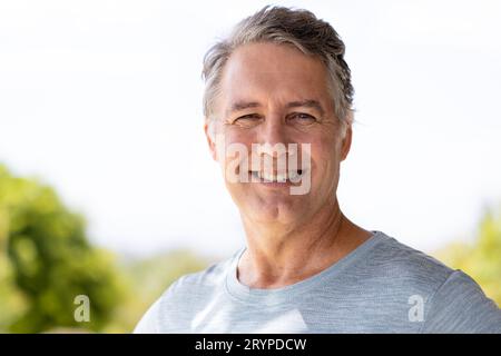 Close-up portrait of handsome caucasian senior man smiling and looking at camera against sky Stock Photo