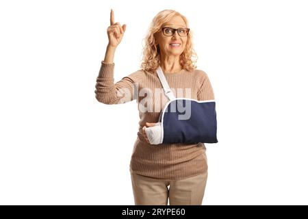 Woman with injured arm wearing a sling and pointing up isolated on white background Stock Photo