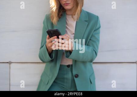 Business woman standing on stairs outside office building while using her cellphone Stock Photo