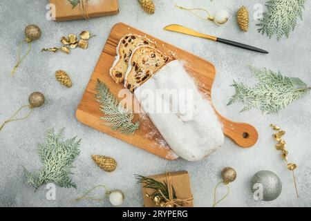 Christmas composition with tasty stollen cake on a wooden board, cutlery on gray table Stock Photo