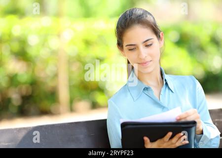 Businesswoman checking documents sitting on a bench in a park Stock Photo