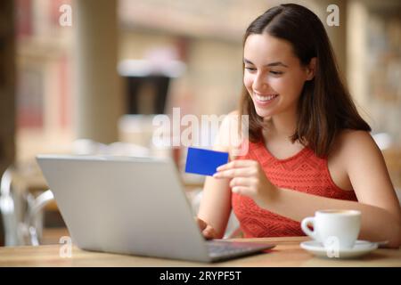 Happy woman with laptop and credit card buying online in a bar terrace Stock Photo