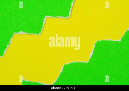 Hole ripped in a green paper on yellow background Stock Photo