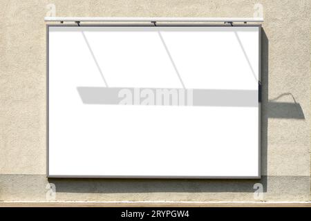 Billboard mockup. Blank advertising poster in frame mounted on building exterior wall with shadow effect. No people. Stock Photo