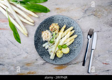 Traditional Bavarian white asparagus with wild garlic- and almond butter dumpling served as top view on a Nordic Design plate wi Stock Photo