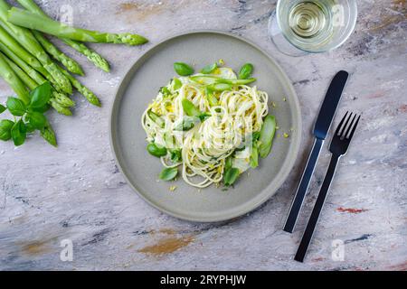 Traditional Italian spaghetti with asparagus in herb sauce served as top view on a Nordic Design plate Stock Photo