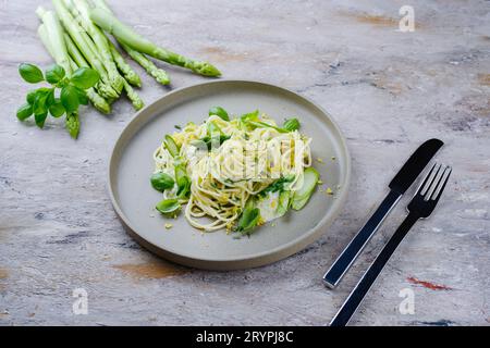 Traditional Italian spaghetti with asparagus in herb sauce served as close-up on a Nordic Design plate Stock Photo