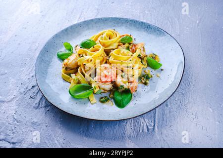 Traditional Italian tagliatelle ai gamberoni pasta with king prawns and herbs served as close-up on a design plate with copy spa Stock Photo