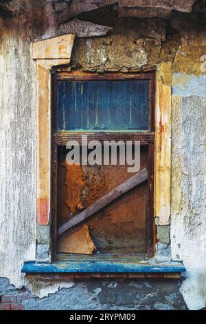 Broken window on old ruined house with worn facade Stock Photo