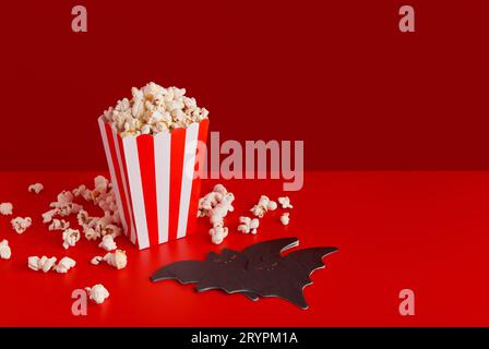 Striped box with popcorn, bat napkin on a red background Stock Photo