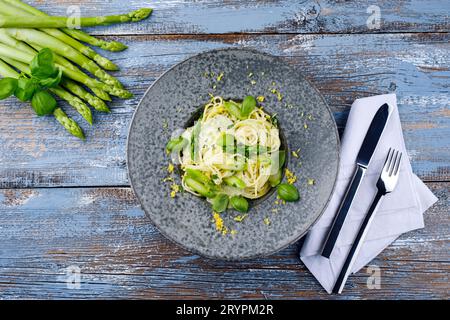 Traditional Italian spaghetti with asparagus in herb sauce served as top view on a Nordic Design plate Stock Photo