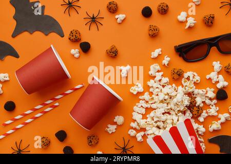 Popcorn, clapperboard, paper cup and halloween decor on a red background. Flat lay, copy space. Stock Photo