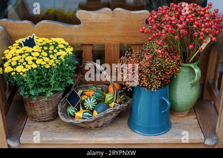 Autumn flowers and basket with pumpkins in flower shop. Halloween and Thanksgiving fall season decoration Stock Photo