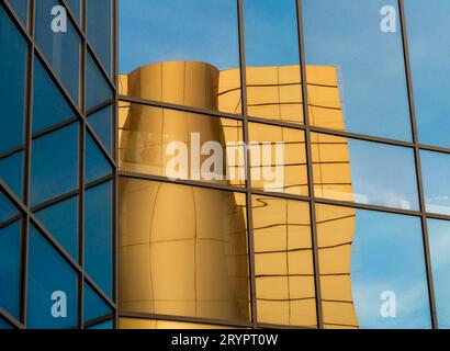 Distorted reflection of a yellow building in the mirrored windows of an office building Stock Photo