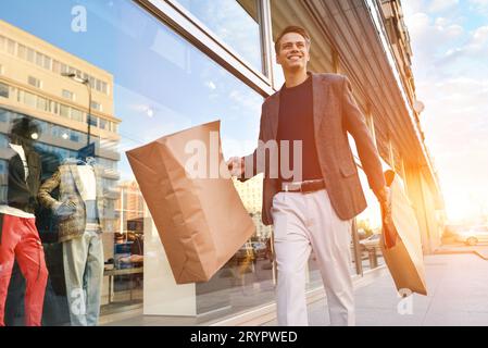 Serious stylish young man walking in urban street and enjoying Black Friday shopping in trendy stores in city Stock Photo