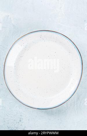 An empty white plate with a blue rim, top shot on a slate background Stock Photo