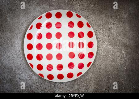 Empty White in red dot ceramic plate On a concrete background. T Stock Photo