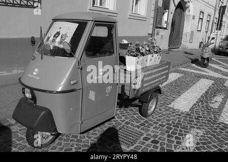 Black and white Heiss and Eis Cafe, smallest coffee shop in Sibiu. Front window for ordering and an auto rickshaw (Tuk tuk) Stock Photo