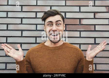 Close up Happy Handsome Man in Trendy Fashion Leaning on Old Brick Wall While Looking at the Camera. Stock Photo