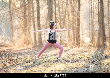 Woman practicing Warrior one yoga pose outdoors Stock Photo