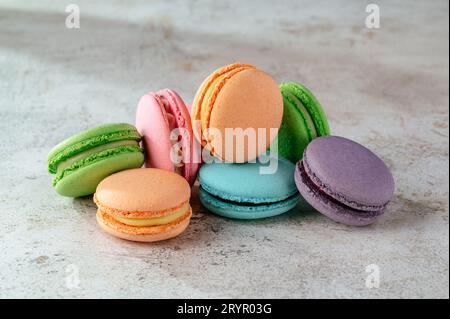 multicolored macaroon cookies lie on a white kitchen table Stock Photo