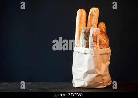 Different types of french bread baguettes in paper bag over dark background with copy space Stock Photo