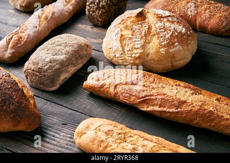 Different types of bread loaves on dark wooden background Stock Photo