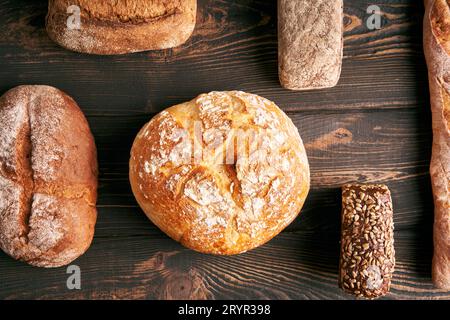 Different types of bread loaves on dark wooden background Stock Photo