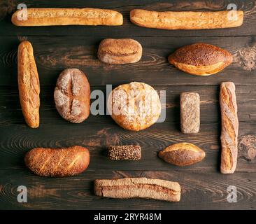 Different types of bread loaves on dark wooden background Stock Photo