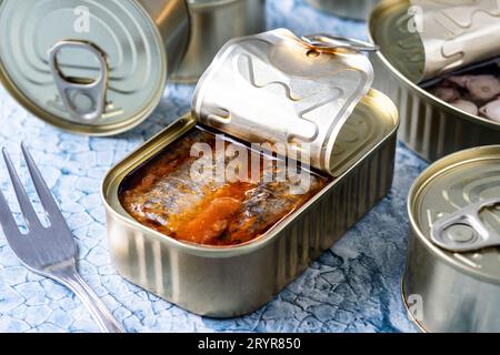 Various canned food in metal cans on blue background Stock Photo