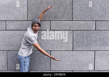 Handsome young man is pointing away, with shocked facial expression Stock Photo