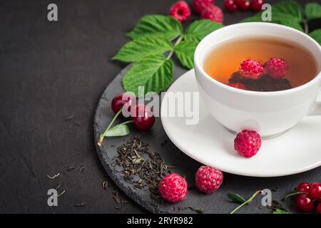 Berry tea and ripe raspberry, cherry, currant on a black background Stock Photo
