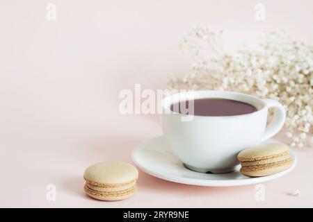 Coffee cup, macaroon and gypsophila flowers on pink background Stock Photo