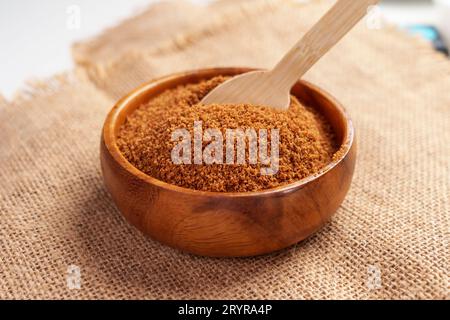 Coco brown sugar made from the kithul palm (Caryota urens) in wooden bowl with bamboo spoon on burlap Stock Photo