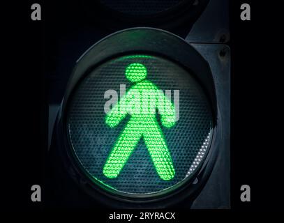 Traffic light with a green man on a black background Stock Photo