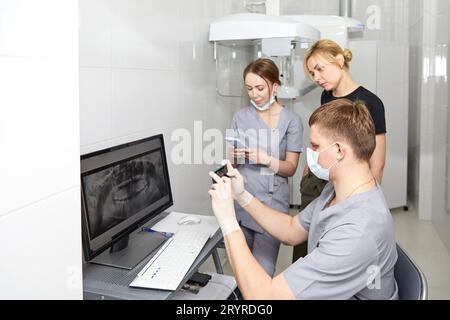 A team of young dentists works in a well-equipped office. Dentists take a picture of the patient's jaws Stock Photo