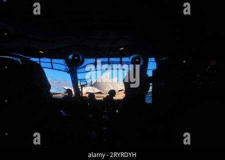 The Sydney Opera House reflected in a distorted Fun House Mirror Image of sunny blue sky with a dark border silhouette of people and columns at OSPT Stock Photo