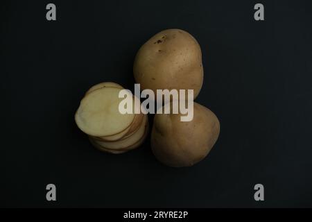 stacked  and whole potato slices on black background. top view Stock Photo