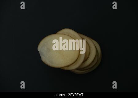 stacked potato slices on black background , top down view Stock Photo