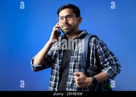 In single color background a happy Indian man talking on smart phone. Stock Photo