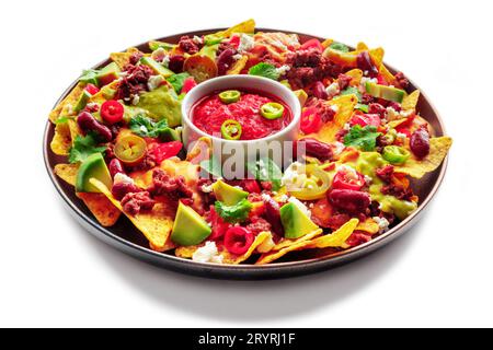 Loaded nachos. Mexican nacho chips with beef, guacamole sauce, cheese salsa, beans and peppers, isolated on a white background Stock Photo