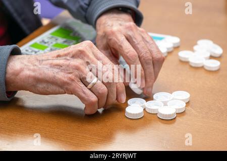 Close up of a senior man playing bingo at Nursing home. leisure game, support, assisted living, and retirement. Stock Photo