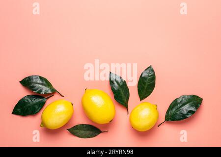 Border of ripe lemons and leaves on a living coral background Stock Photo