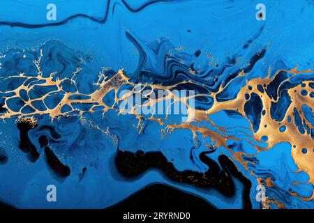 Fluid Art. Liquid Metallic Gold and gold powder particles in abstract blue wave. Marble effect background or texture Stock Photo