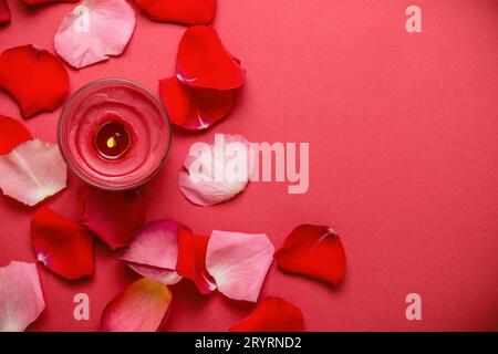 Candle and rose petals on a red background. Stock Photo